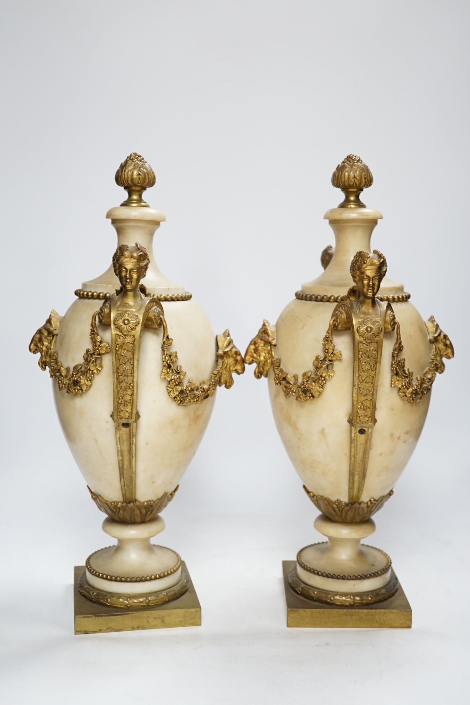 A pair of Adam style gilt metal mounted alabaster urns, 42cm high